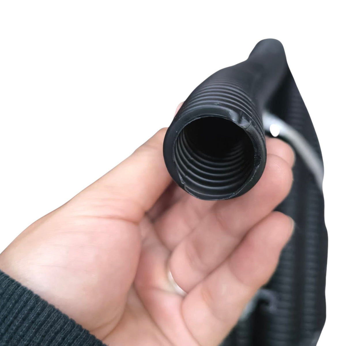 A close-up of a hand holding a black corrugated hose connector with a threaded male end, against a plain white background.