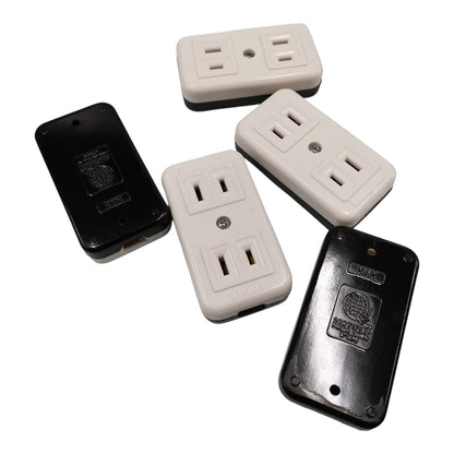 Four plastic outlet covers arranged on a white background, showing both front and back views. Two covers are off-white/cream and two are black.