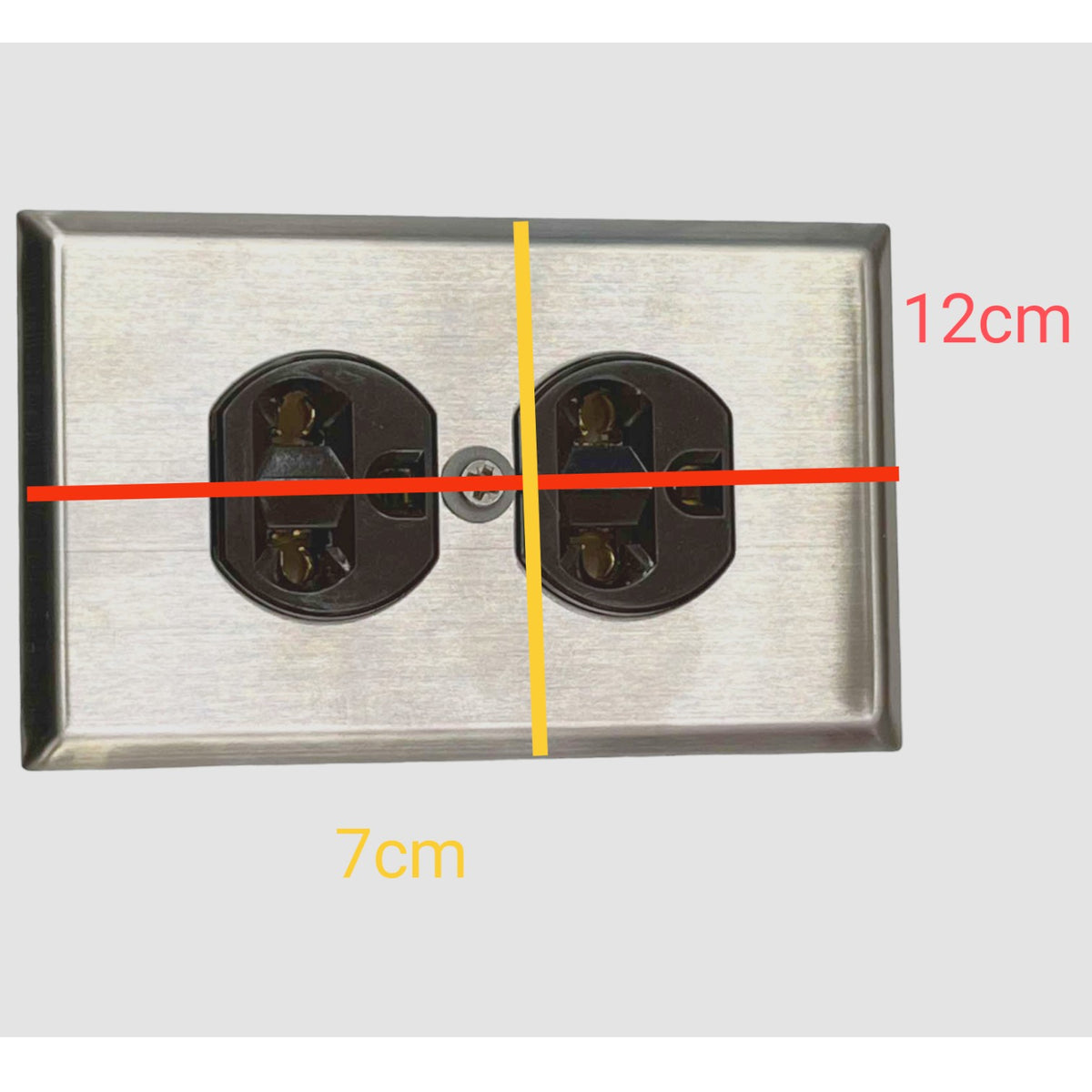 A brushed metal double electrical outlet cover shown on a light gray background with overlaid dimension lines and text indicating 12 cm width, 7 cm depth, and a vertical center line.