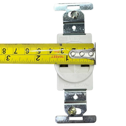 A white electrical outlet with metal mounting brackets on both sides, shown with a yellow tape measure spanning the front to indicate its width. The outlet has embossed text reading '15A 250VAC'.