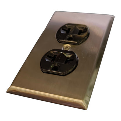 A brushed brass or bronze electrical outlet cover plate with two black outlets, shown at an angle on a white background.