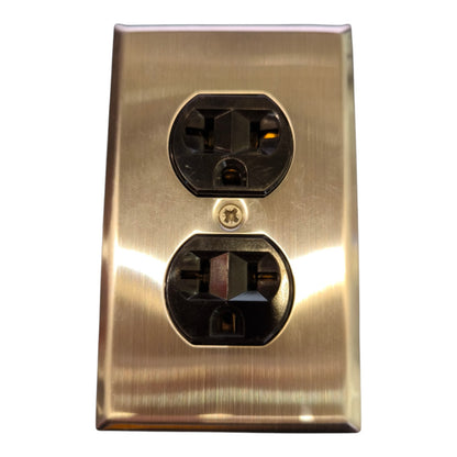 A brushed brass or gold metal double outlet electrical panel cover on a plain white background.