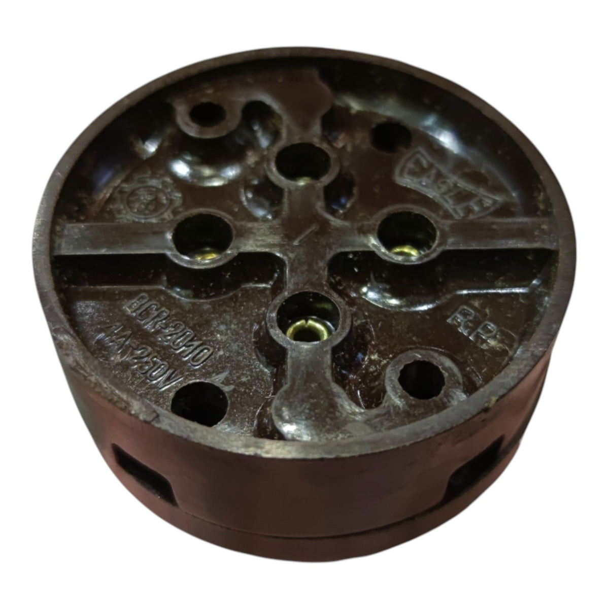 A dark brown cast iron or steel mechanical component with multiple circular holes and embossed text, shown on a plain white background.
