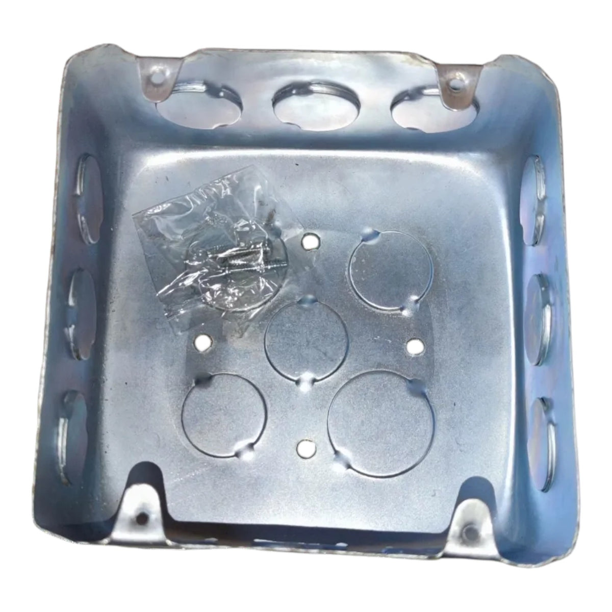 A square metal electrical junction box with pre-drilled screw holes and a small clear plastic bag of mounting screws inside, shown on a plain white background.