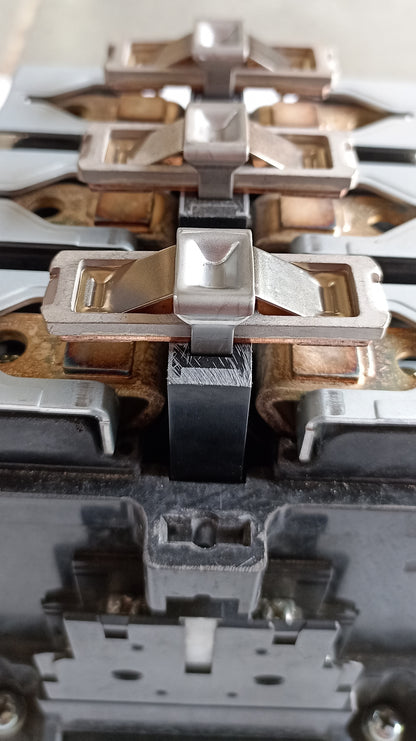 Close-up of a multi-socket electrical outlet or switch component showing metal terminals, copper contacts, and black plastic housing.