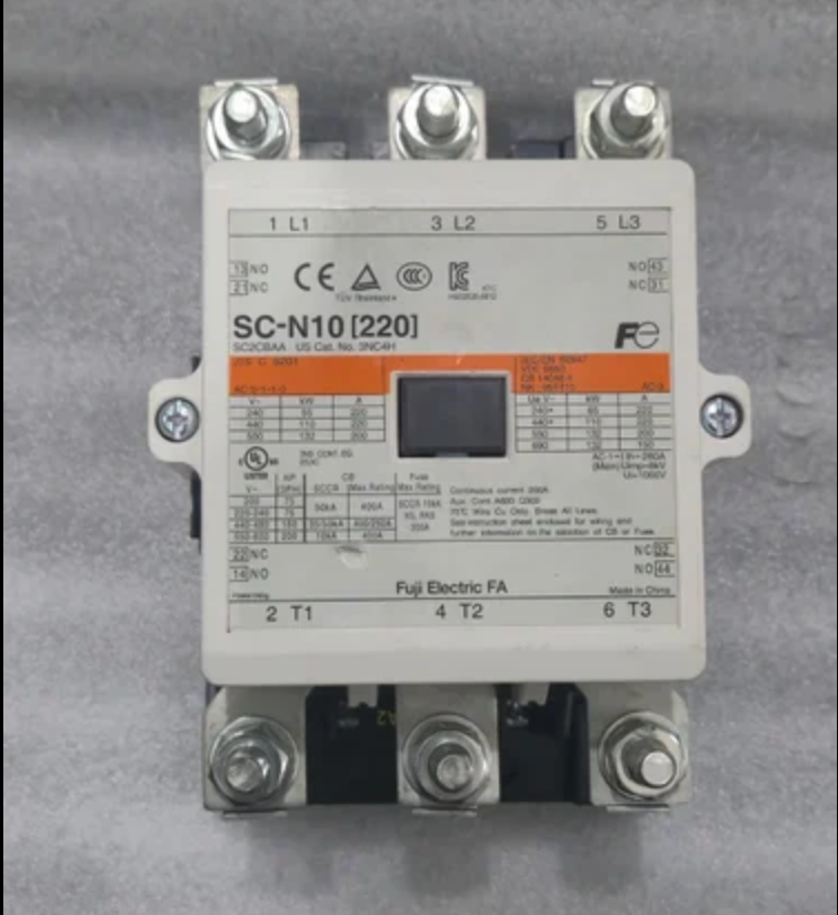A Fuji Electric contactor, model SC-N10 (220), featuring a white plastic housing with technical specifications printed on the front, three silver screw terminals at the top, and three black screw terminals at the bottom, set against a gray textured background.