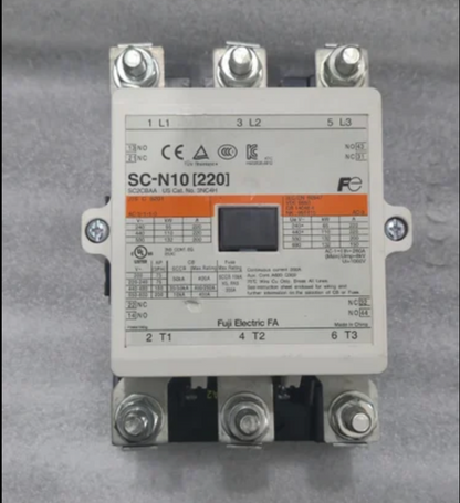 A Fuji Electric contactor, model SC-N10 (220), featuring a white plastic housing with technical specifications printed on the front, three silver screw terminals at the top, and three black screw terminals at the bottom, set against a gray textured background.