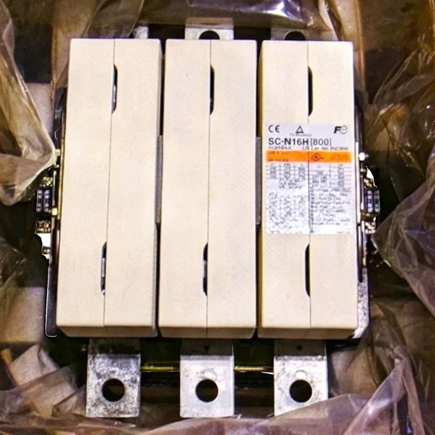 Three large industrial electrical contactors with beige plastic enclosures and metal terminal bases, shown wrapped in protective plastic with a product label visible on the right unit.