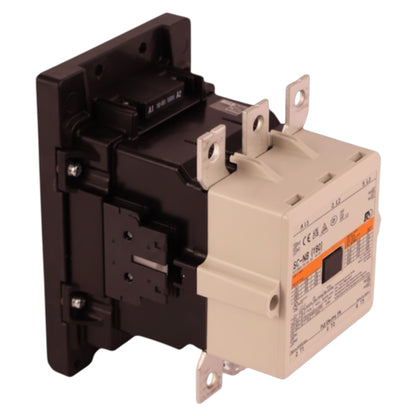 An industrial electrical contactor with a black main body and a beige terminal housing, featuring metal mounting tabs and a small orange label on the front.