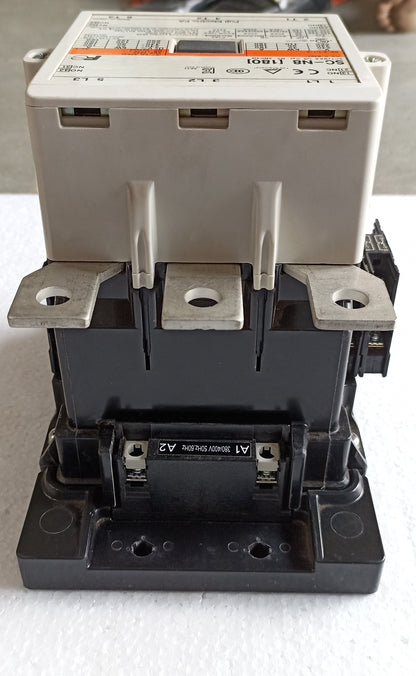 A heavy-duty electrical contactor with a beige upper housing and a black lower base, photographed on a white textured surface.
