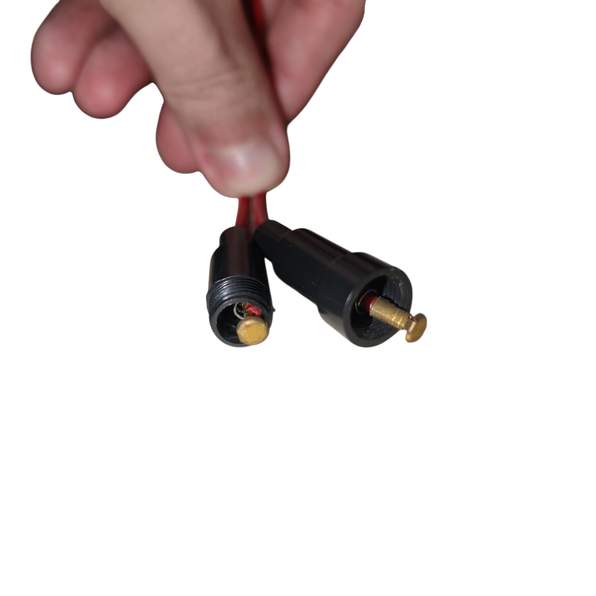 A close-up of a hand holding a pair of red wire connectors with black plastic housings and brass screw terminals against a plain white background.