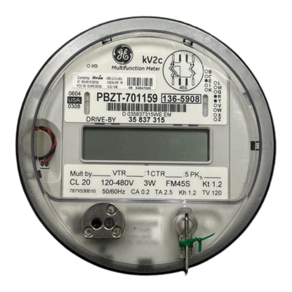 A round GE multifunction electricity meter with a digital display screen, technical specifications printed on the label, and metal terminals on a white background.