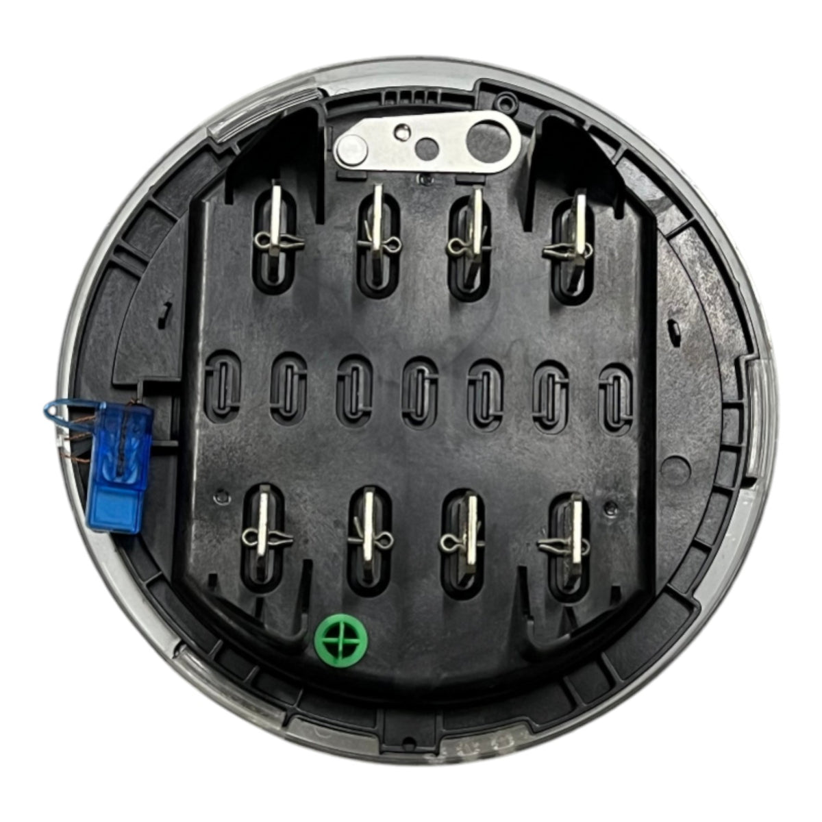 A circular black plastic battery compartment or terminal cover with multiple metal screw terminals, a blue wire connector on the left, and a green plus sign symbol near the bottom, shown on a white background.