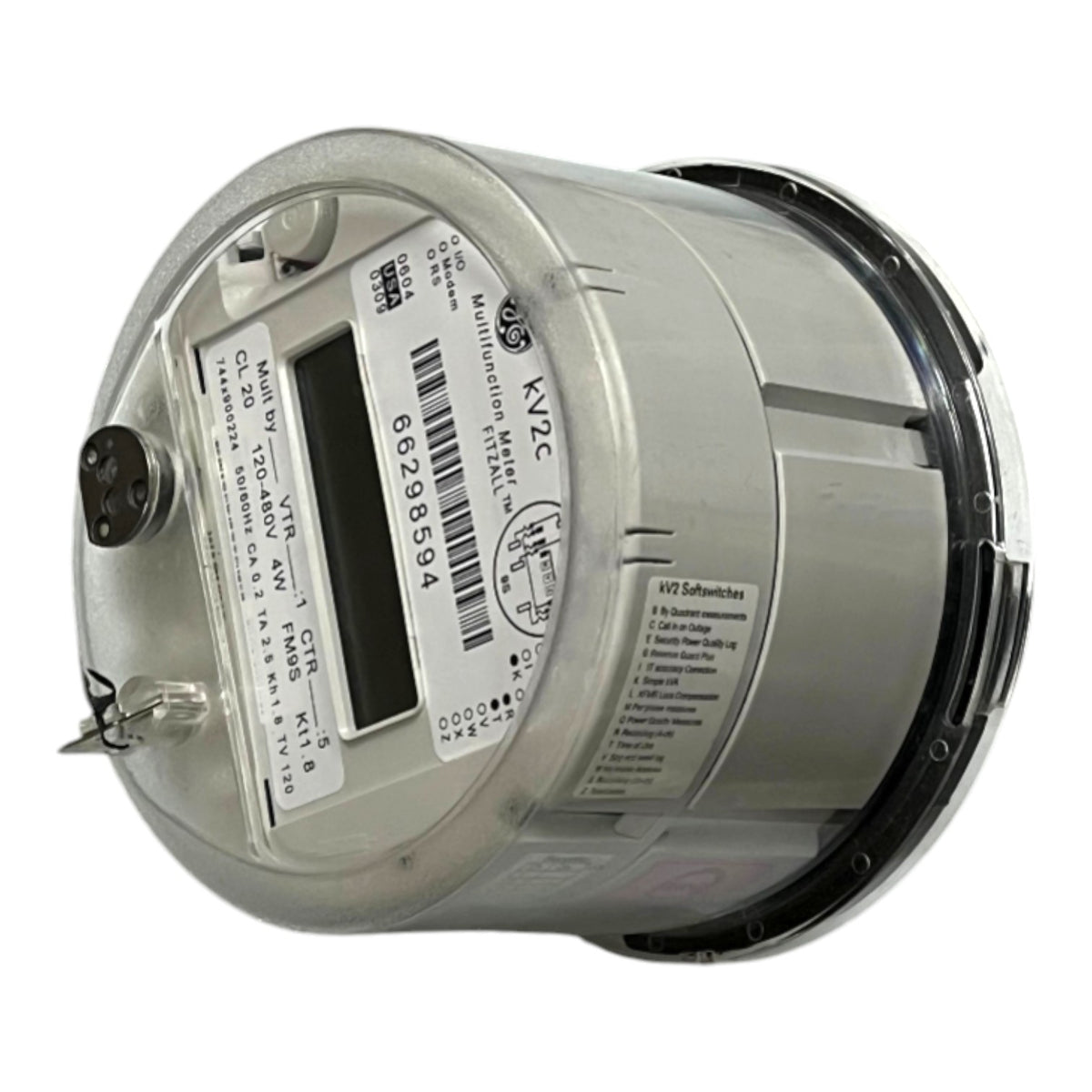 A silver cylindrical industrial electricity meter with a clear protective cover, featuring a digital display window, barcode, and technical specifications printed on the side.