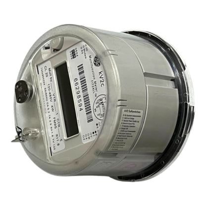A silver cylindrical industrial electricity meter with a clear protective cover, featuring a digital display window, barcode, and technical specifications printed on the side.