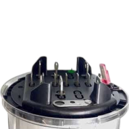 A close-up of a circular black electrical terminal block or connector with multiple metal pins and a small pink wire, set against a plain white background.