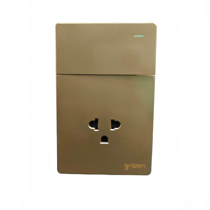 A modern wall outlet socket with a metallic gold finish, featuring a three-pin UK plug and the 'grazen' brand name printed in gold near the bottom right corner, set against a plain white background.