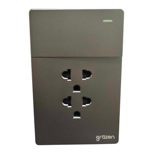 A dark gray wall outlet cover with a single UK three-pin socket visible, featuring the 'grözen' brand logo in the bottom right corner.