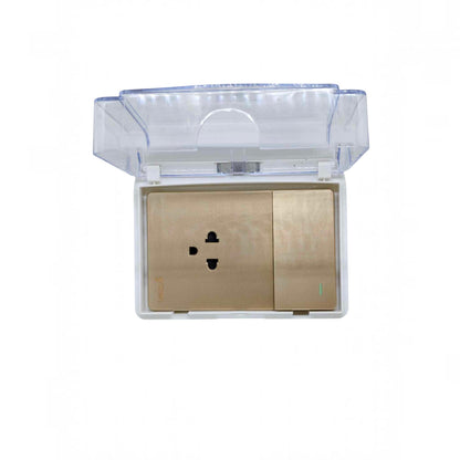 A gold-colored electrical outlet cover plate with a transparent waterproof plastic lid, shown against a plain white background.