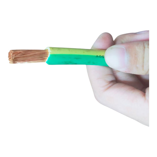 A close-up of a hand holding a green and yellow electrical wire cable with exposed copper-colored strands on a plain white background.