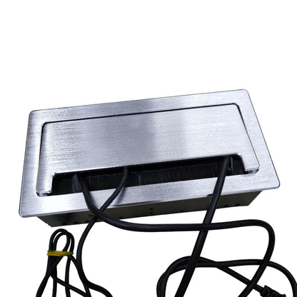 A brushed stainless steel under-cabinet electrical outlet cover with a black cable slot and visible black power cords, shown on a plain white background.