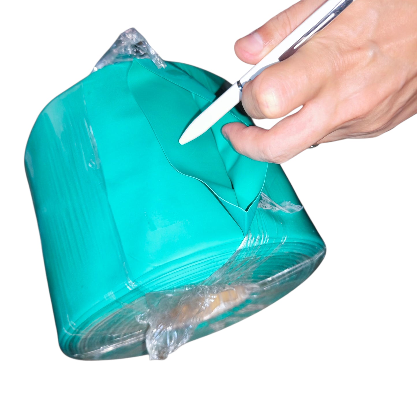 Hand cutting a roll of green cellophane with scissors on a white background