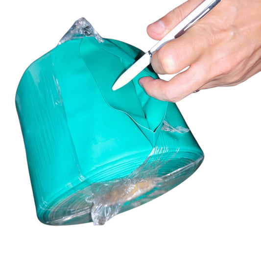 Hand cutting a roll of green cellophane with scissors on a white background