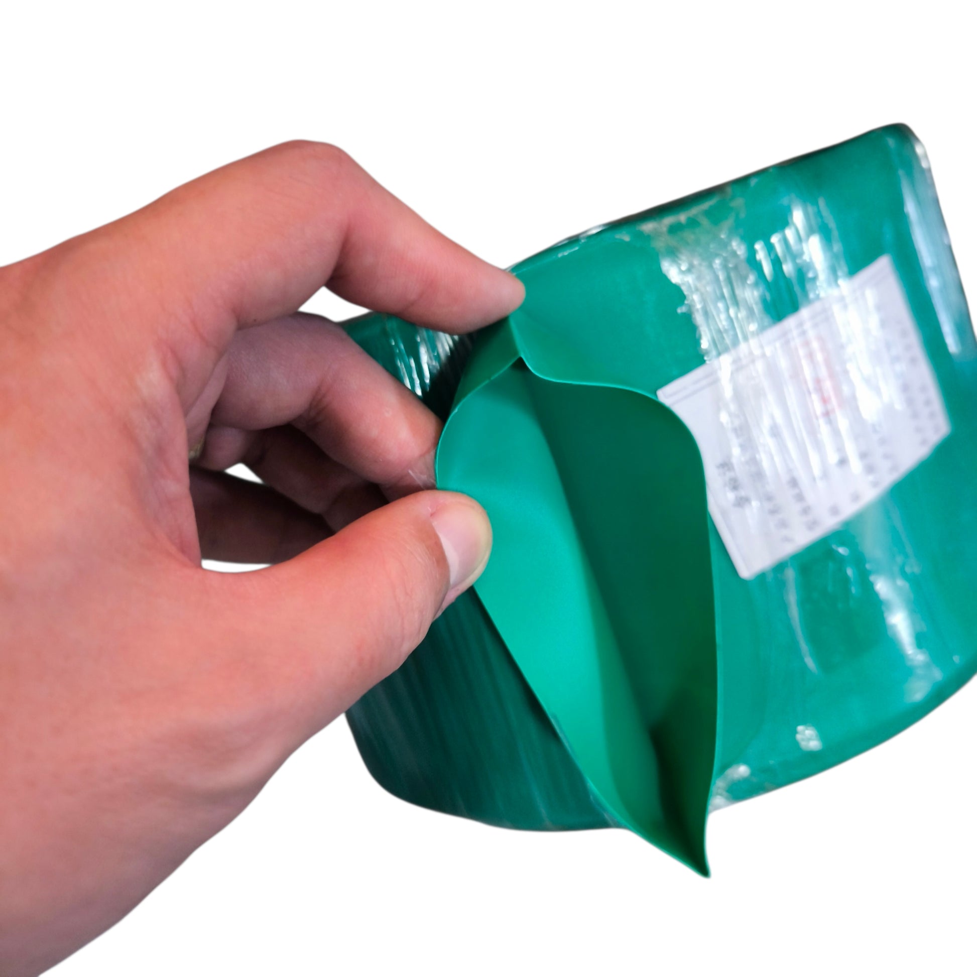 Hand holding a green plastic container with a white label on a white background