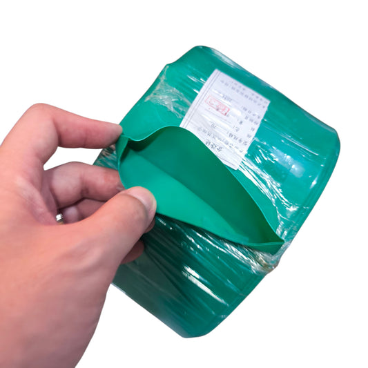 Hand opening a green plastic bag with a white label on a white background