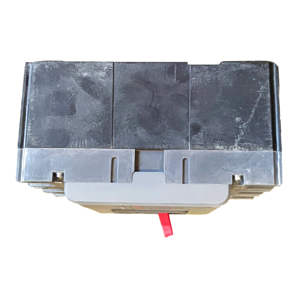 A used black plastic automotive or industrial component housing with a gray metal base and a small red tab protruding from the front, shown on a white background.