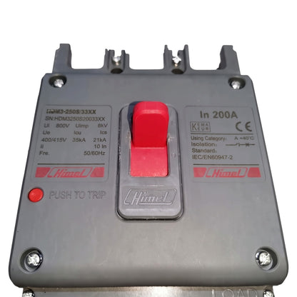 A Himpel industrial circuit breaker with a gray plastic housing, a prominent red central switch, a red push-to-trip button, and technical specifications printed on the front.