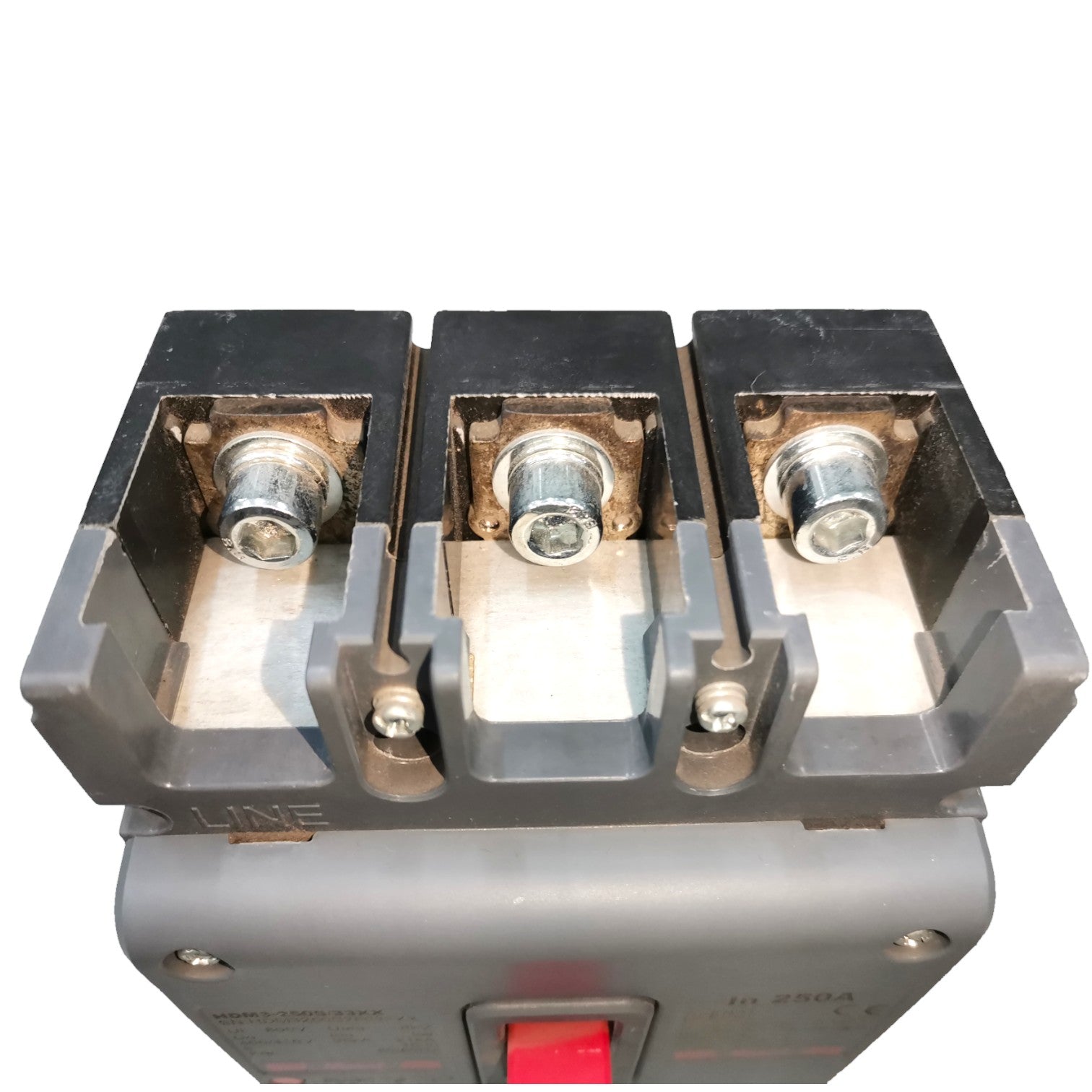 A close-up of a three-terminal electrical contactor or switch component with metal screw terminals and a red switch lever on a gray housing, isolated on a white background.