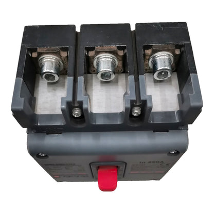 A three-pole electrical circuit breaker with a gray plastic housing, three silver metal terminal posts on top, and a red front handle, shown on a plain white background.