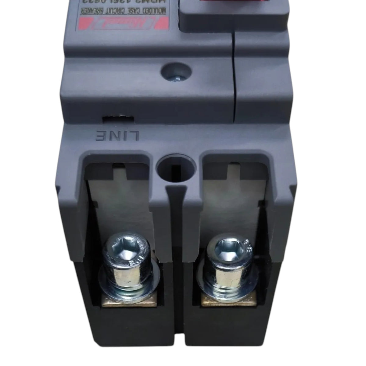 A close-up of a dark gray electrical circuit breaker component with metal terminal screws and a small red label on a white background.