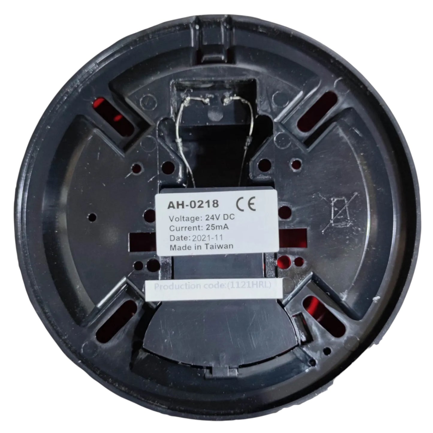 The underside of a round black plastic electrical component, likely a thermostat or similar home automation device, featuring a white label with technical specifications and red internal contacts.