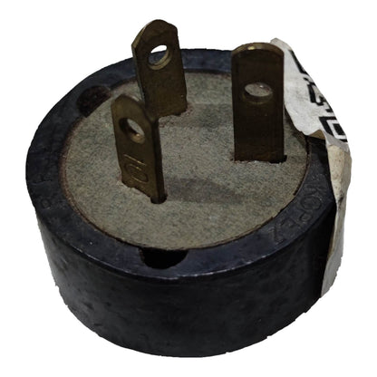 A circular black electrical component with three metal pins and a partially peeled white label, shown on a white background.