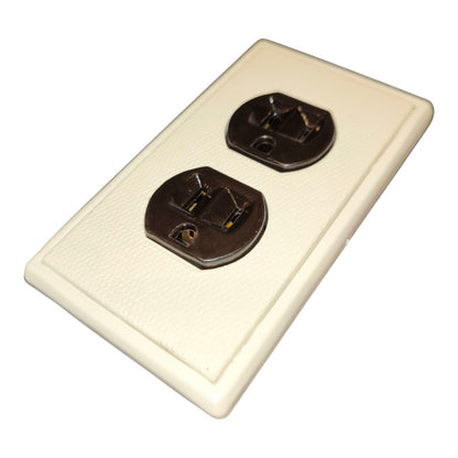 An off-white textured plastic double outlet cover plate with two dark metal sockets, shown on a plain white background.