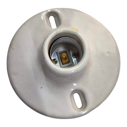 A round ceramic light socket base with a central threaded contact point and two mounting slots, shown on a plain white background.