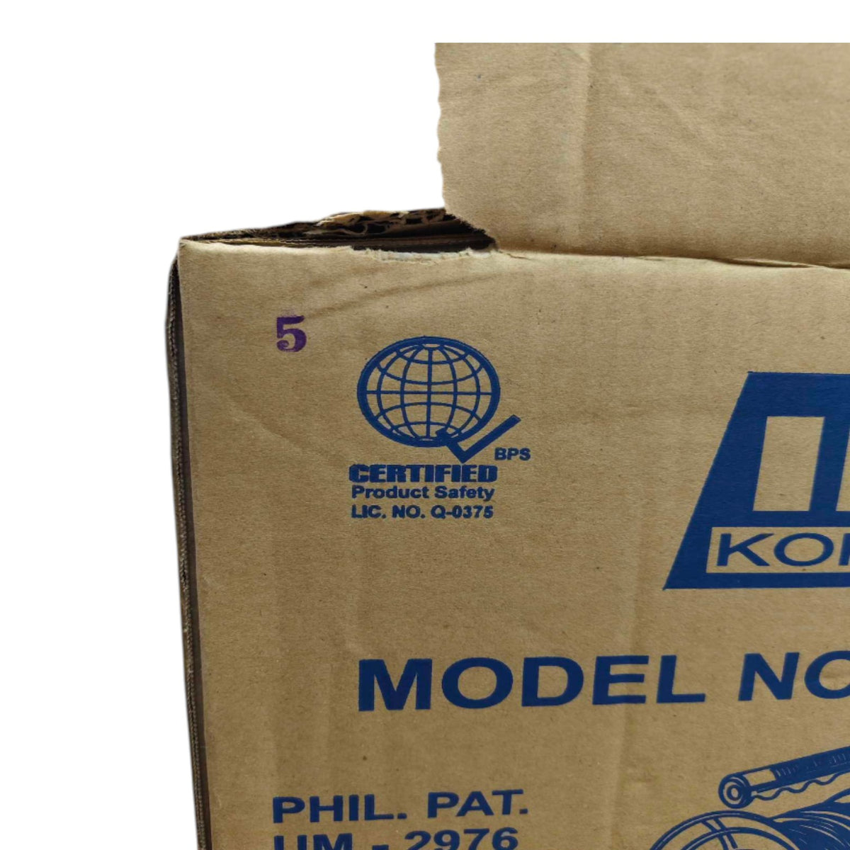 Close-up of a brown corrugated cardboard box with blue printed text and logos, including a BPS certified product safety mark and partial model text.