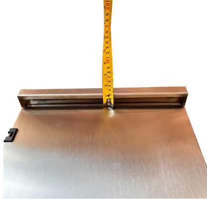 A brushed metal rectangular panel with a brass-colored mounting bracket and a yellow tape measure standing vertically against the top edge, shown on a plain white background.