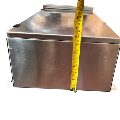 A stainless steel rectangular metal box with a lid, shown against a white background with a yellow tape measure standing vertically to indicate its height.