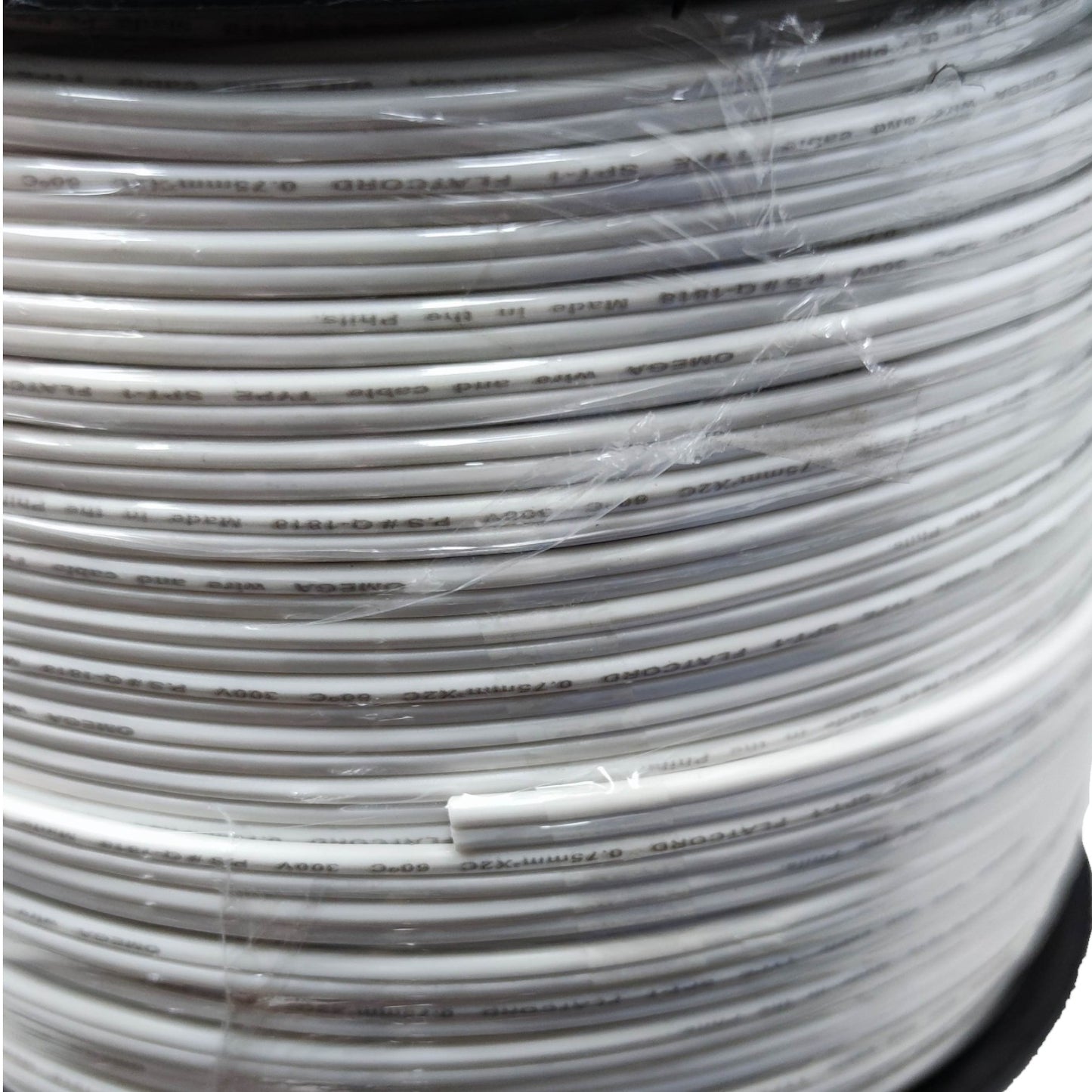 A close-up of a spool of white flat cable wrapped in clear protective plastic, with printed text visible on the cable.