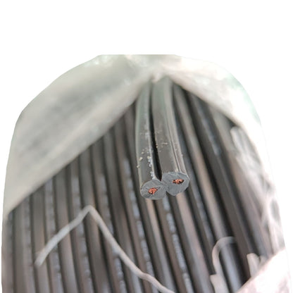 A bulk bundle of black electrical cables or wires bundled inside a translucent plastic bag, with two cable ends exposed showing the cross-section and copper-colored inner conductors.