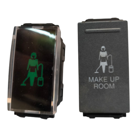 Two industrial toggle switches side by side on a white background. The left switch has a clear cover showing a green illuminated symbol of a person with a vacuum cleaner.