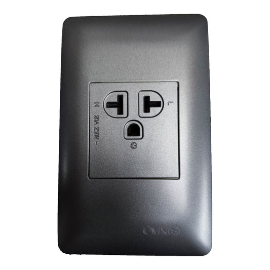 A dark gray wall outlet cover plate with a recessed center panel showing two flat grounding pins and a grounding hole, photographed on a plain white background.