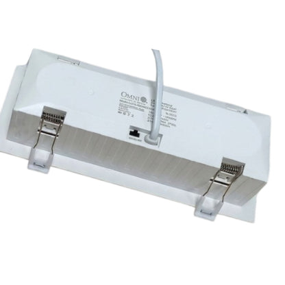 White rectangular ceiling light fixture trim with two metal mounting clips and a white power cord, shown on a plain white background. The brand name OMNI is visible on the top surface.