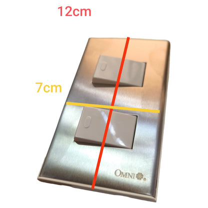 A brushed metal double light switch plate shown on a white background with red and yellow dimension lines and text indicating 12cm by 7cm measurements. The brand name OMNI is visible near the bottom.