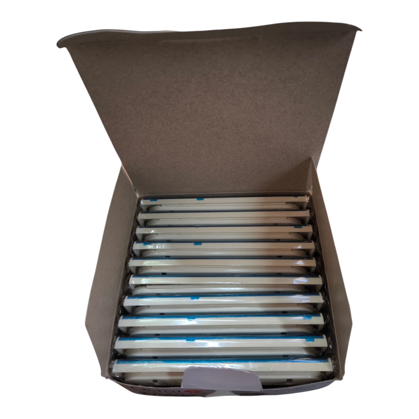 An open brown cardboard box containing multiple long, narrow white items wrapped in clear plastic with blue tape accents, photographed on a plain white background.