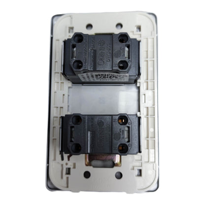 A close-up of a white electrical wall switch plate showing the internal components, including two black contact blocks and a central silver spring, on a white background.