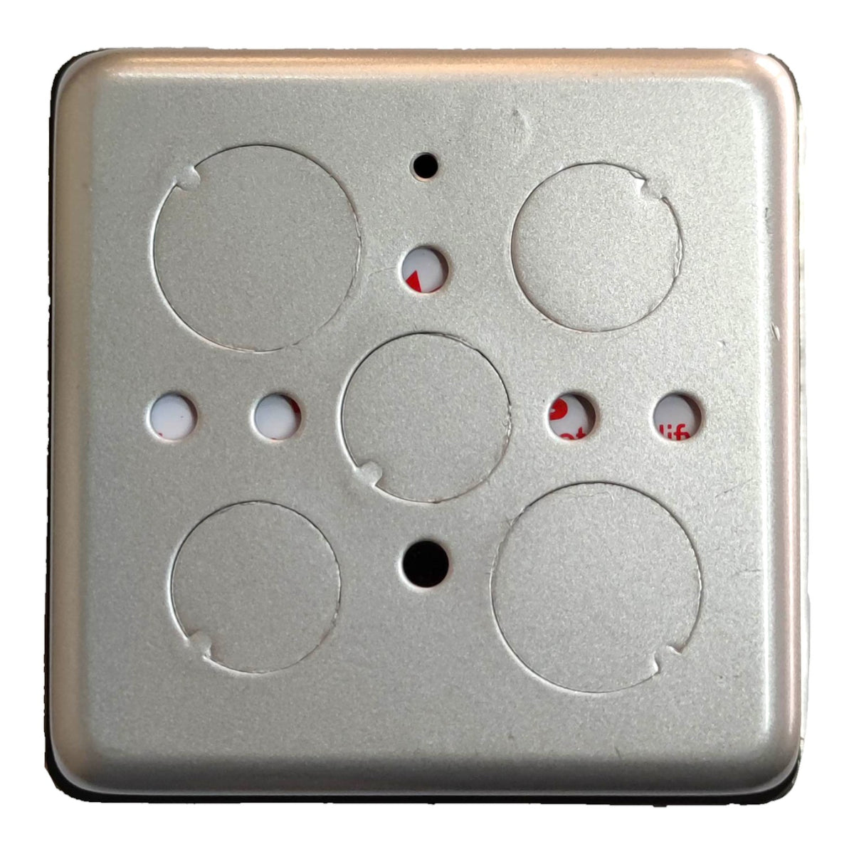 A square metallic wall plate or electrical outlet backplate with circular cutouts and small holes, shown against a plain white background.
